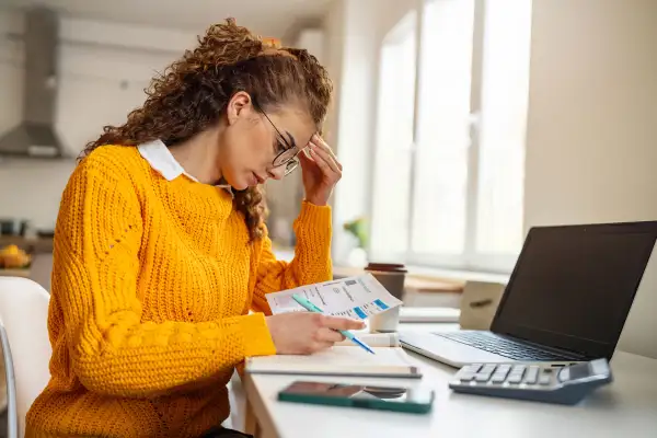 Worried woman looking at receipts at her home