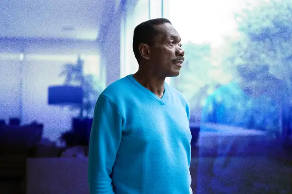 Senior man looking outside through a window in his home